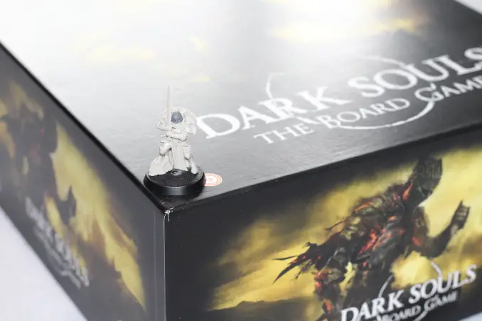 Caja de juego de mesa Dark Souls con comparación de miniaturas