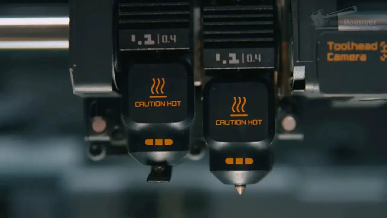 Front close-up of the Bambu X2D dual-nozzle hotends showing both nozzles and caution hot indicators