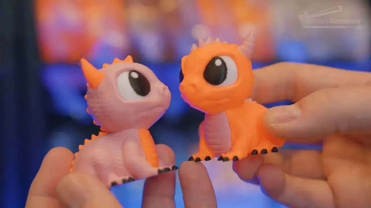 Close-up of two orange and white printed figurines on a workbench