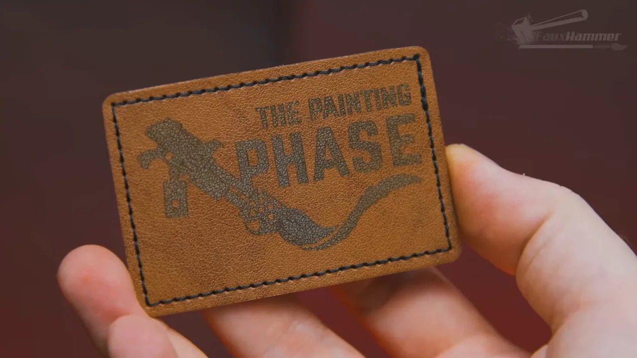 Engraved leather patch with text reading 'THE PAINTING IS SCARED'