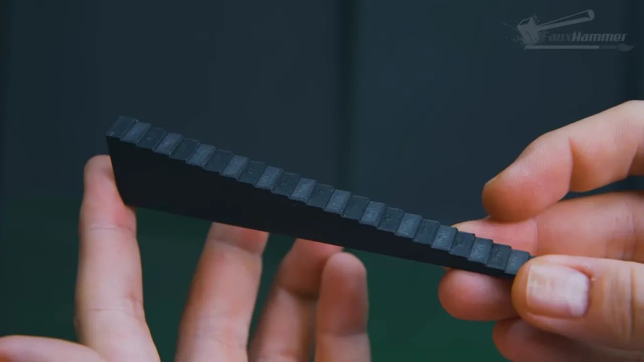 Hand holding a dark stepped strip with raised rectangular sections for height testing