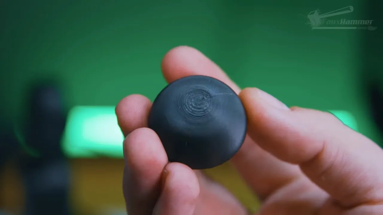 Hand holding a printed circular cylindrical object with concentric target-like pattern