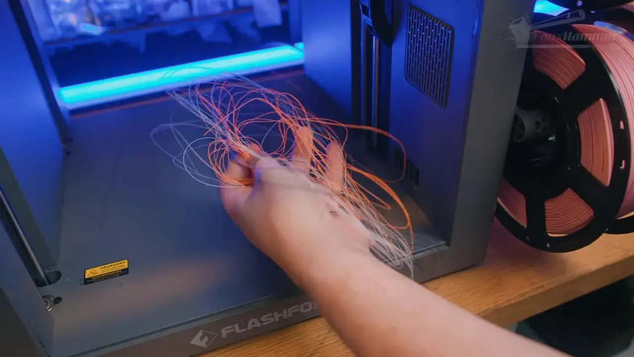 Hand feeding loose filament into the FlashForge Creator 5 interior during material loading