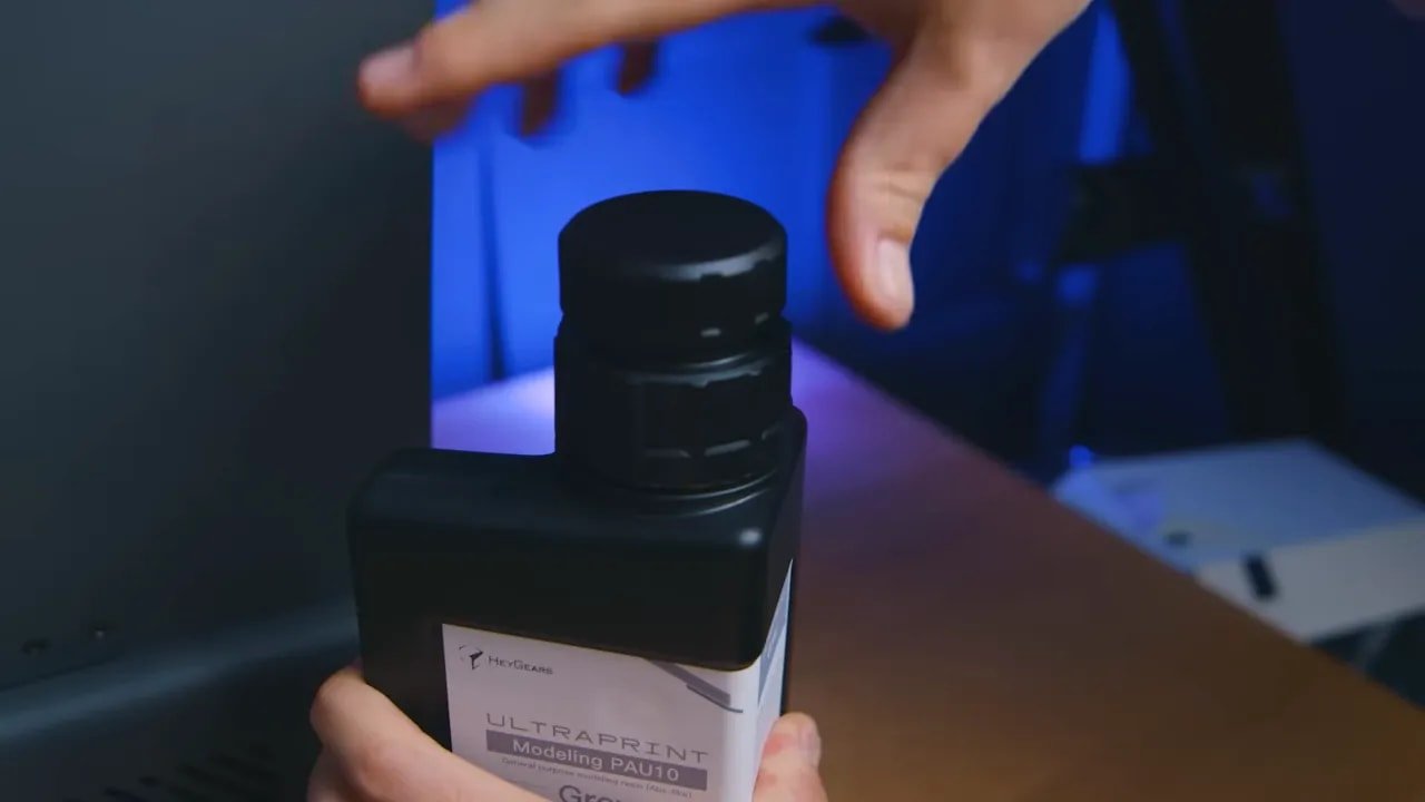 Hand holding HeyGears resin bottle in front of the Reflex printer