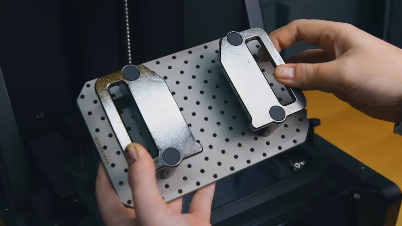 Hands setting a resin print on a perforated work tray during HeyGears Reflex cleanup