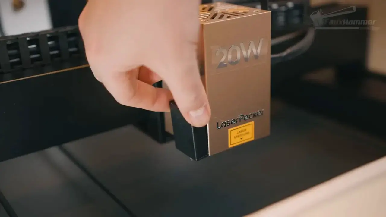 Hand holding the 20W LaserPecker LX2 laser head module above the bed