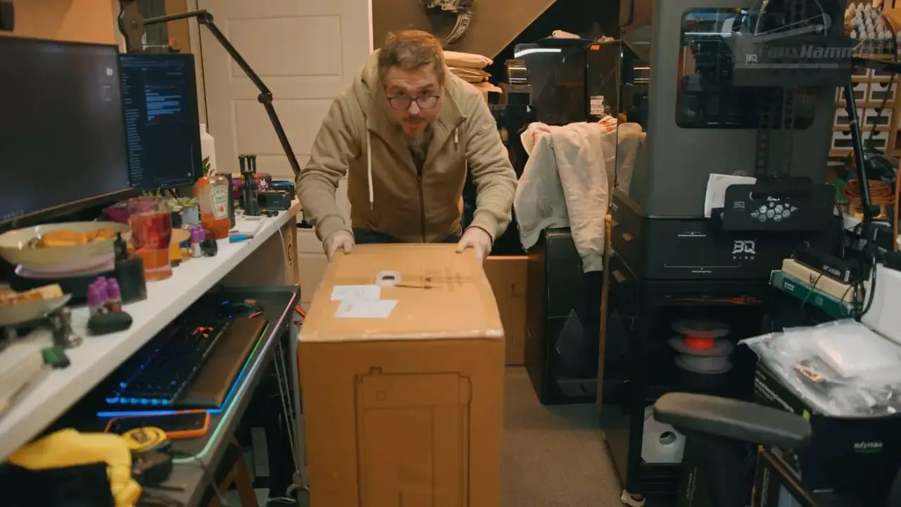 Reviewer carrying a large LaserPecker LX2 shipping box in the workshop