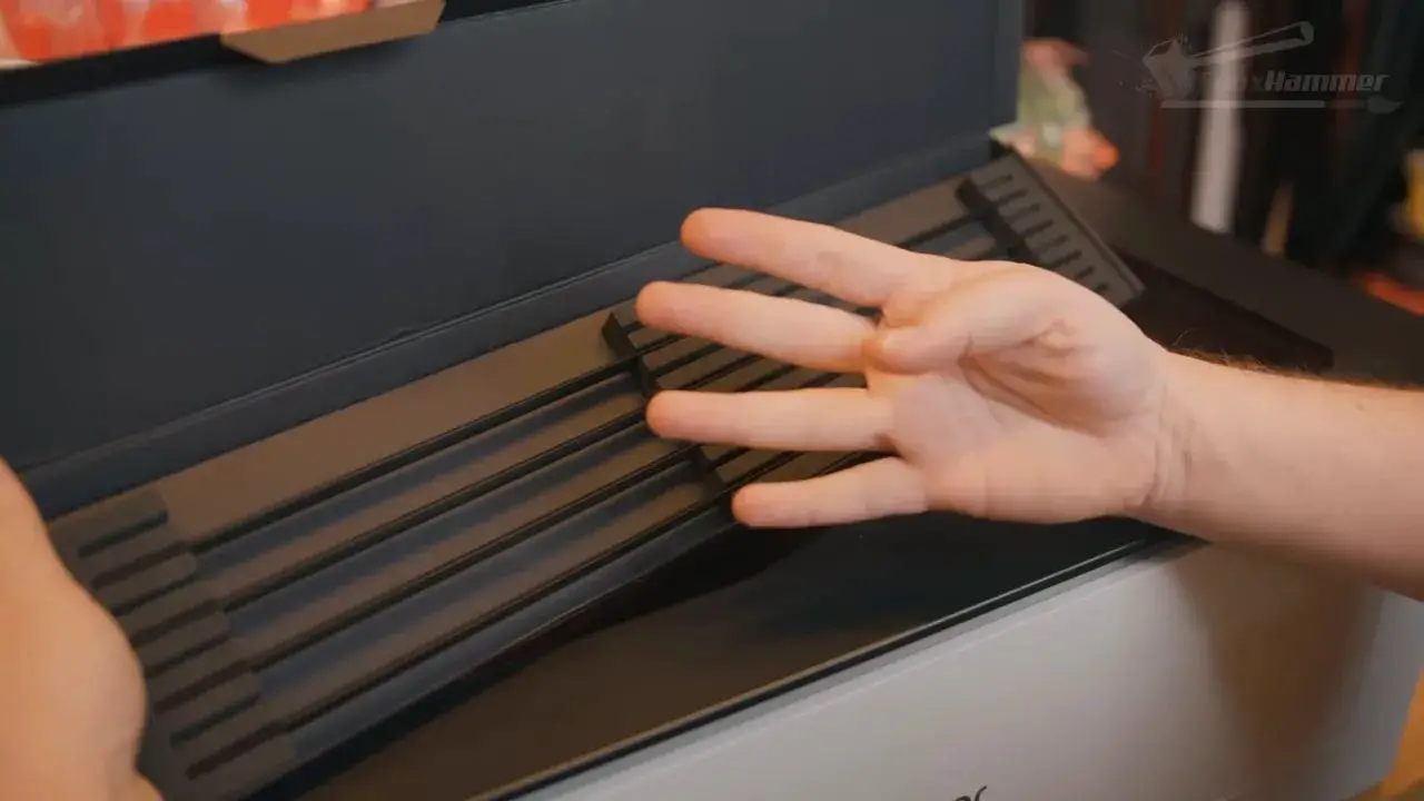 Hand gesturing over slats inside the LaserPecker LX2 enclosure