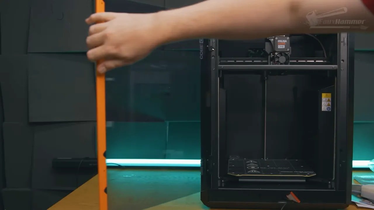 Prusa Core One enclosure opened with a hand adjusting items inside the build area