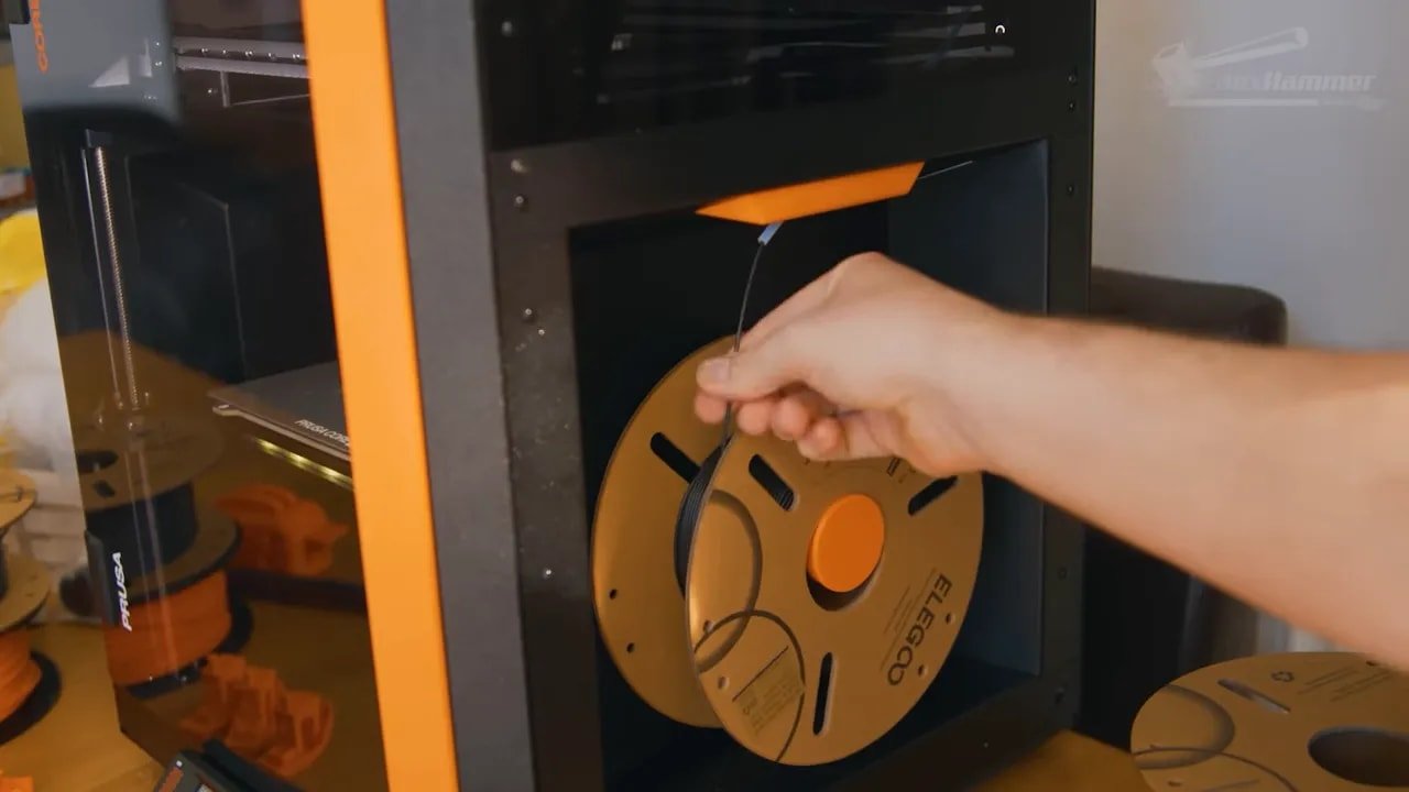 Hand inserting filament into the Prusa Core One enclosed spool and PTFE feed path