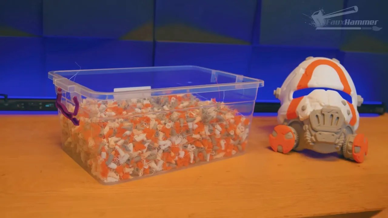 Multi-colour 3D printed parts in a clear bin alongside a matching prop figure